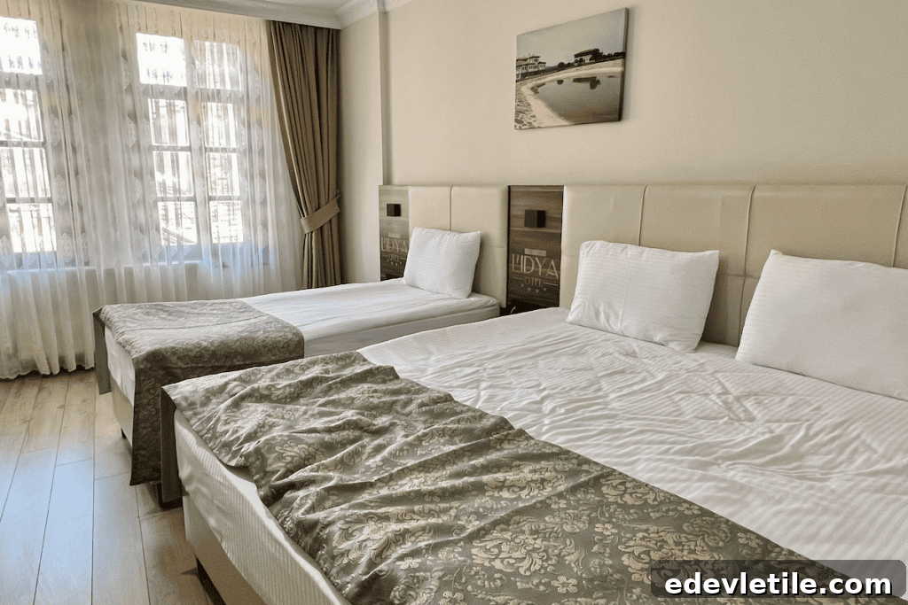 Bright, modern hotel room in Kastamonu with twin and double beds, light wood floors, and large curtained windows.