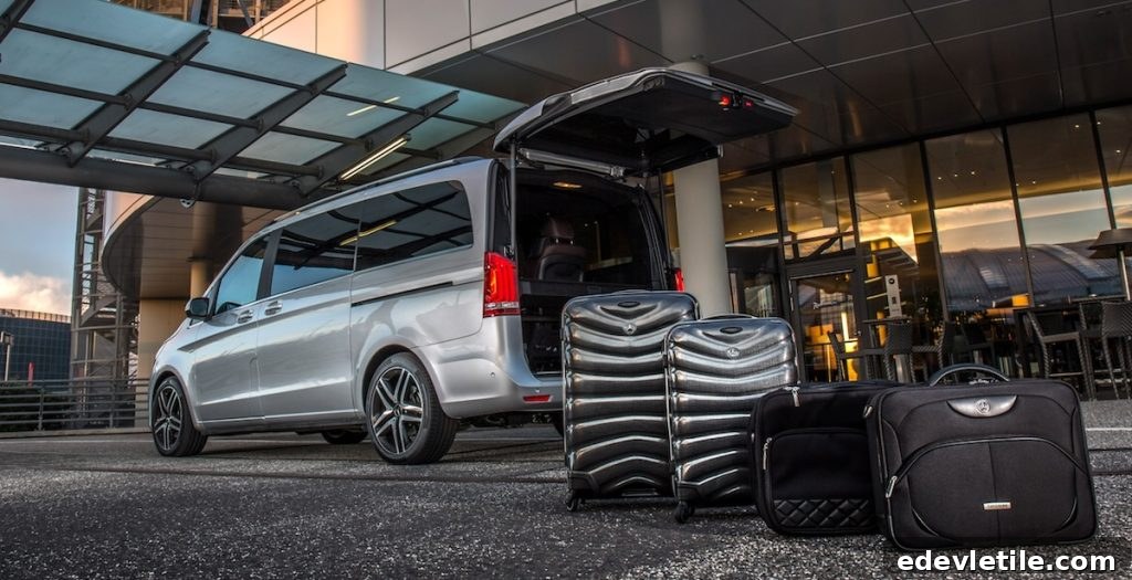 Private transfer van parked outside a hotel entrance with suitcases placed beside the open trunk.