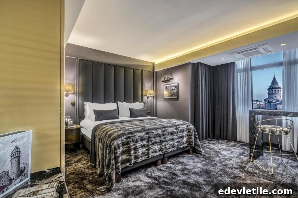 Sleek hotel bedroom with dark, moody decor and a floor-to-ceiling window offering a framed view of the Galata Tower at dusk.