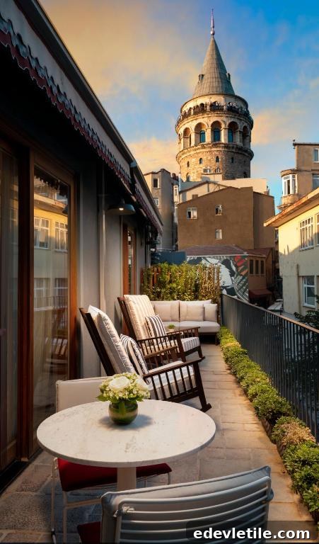 Cozy hotel terrace with cushioned rocking chairs and a table, set against an up-close view of the Galata Tower under soft evening light.