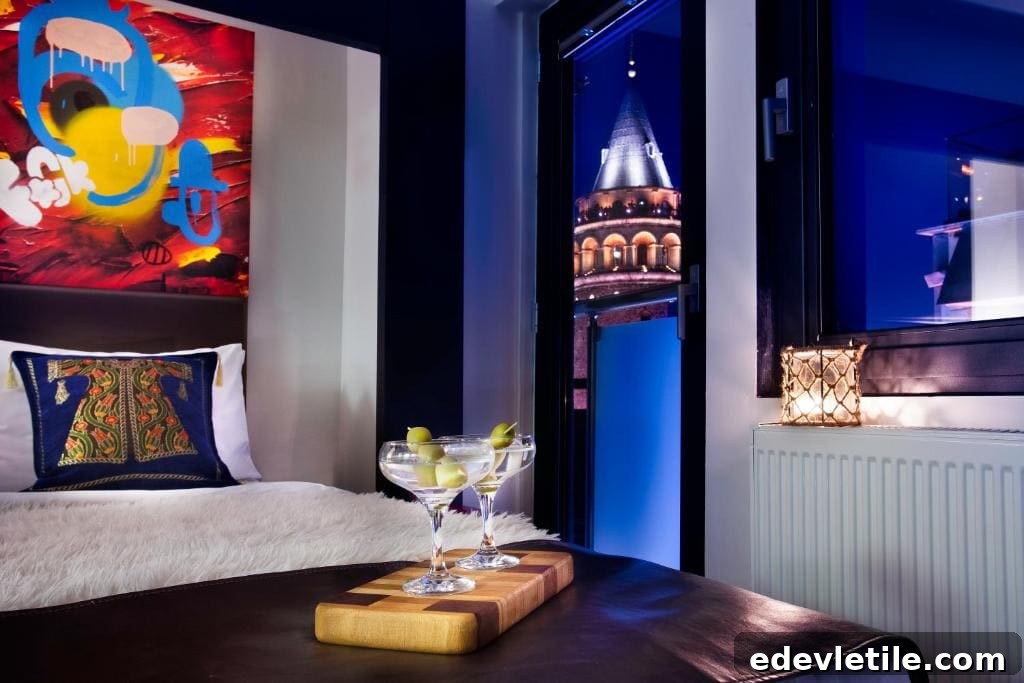 Stylish hotel room with modern decor, two cocktails on a table, and a dramatic night view of the illuminated Galata Tower.