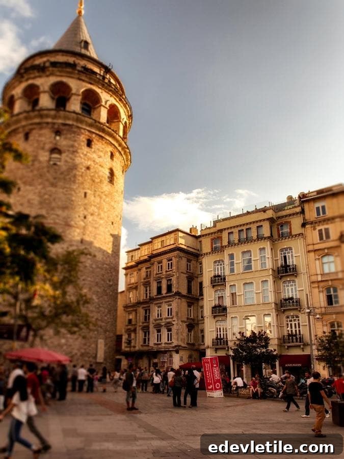 Evening scene of the Galata Tower and neighboring architecture as people gather in the lively plaza below.