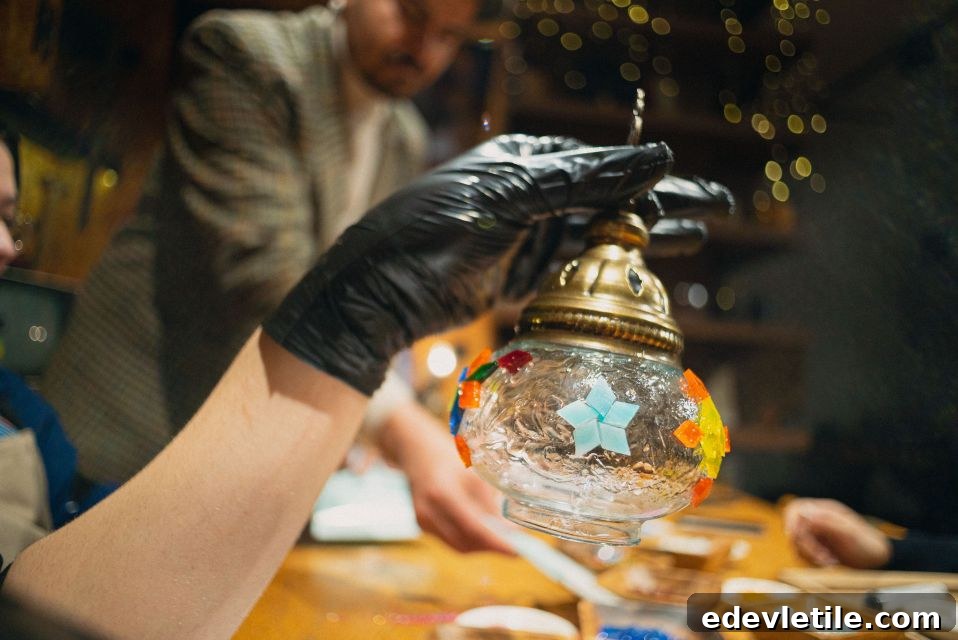 Hand holding up a nearly finished mosaic lamp during a DIY workshop in Istanbul, with colorful tiles and blurred background lights.