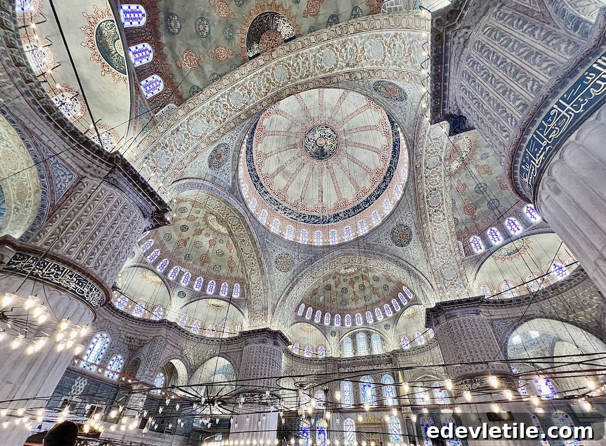 Interior of the Blue Mosque in Istanbul, showcasing intricate Iznik tile patterns, stained glass windows, massive columns, and soft warm lighting.