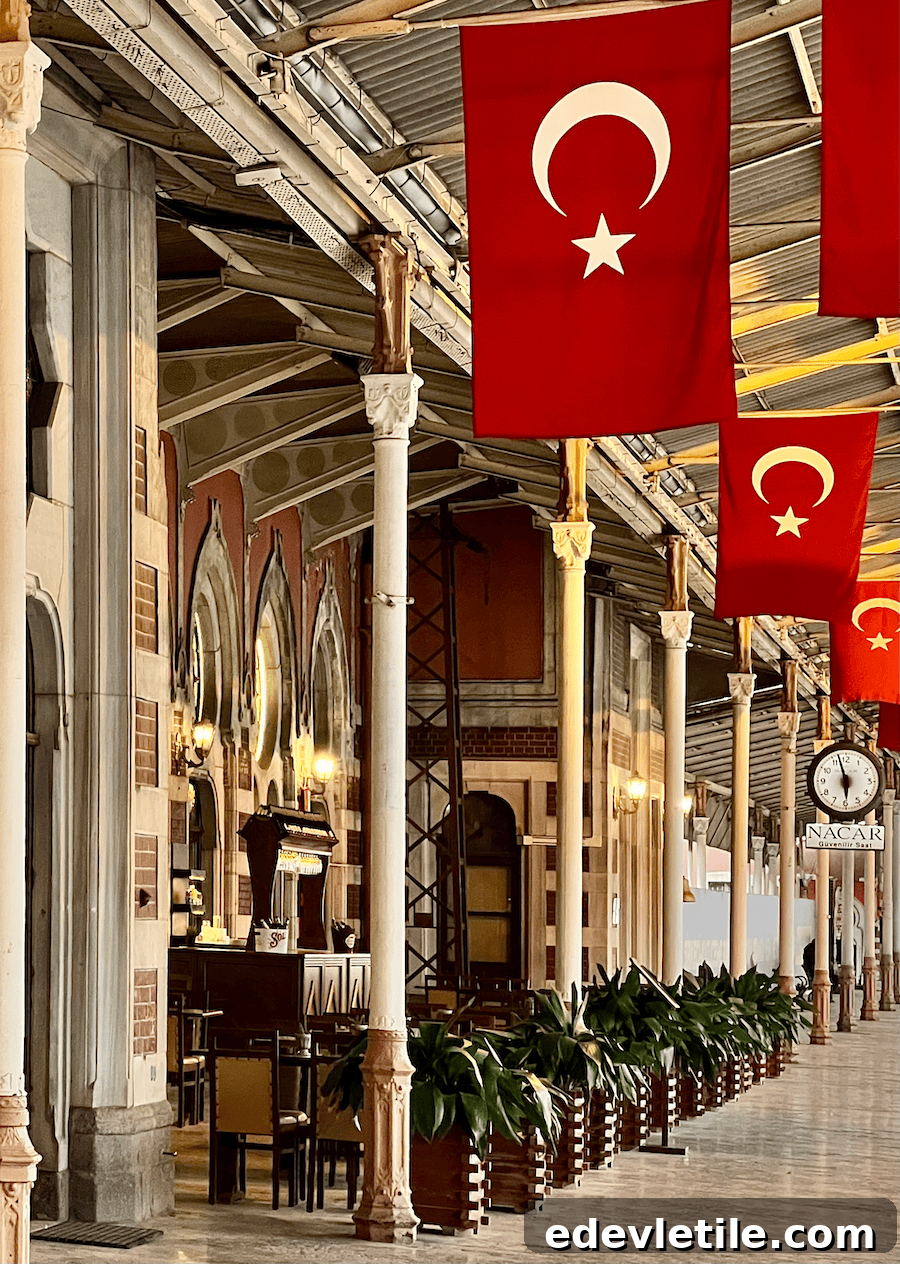 Platform at Istanbul’s Sirkeci Station with rows of Turkish flags hanging from the ceiling, vintage lighting, arched windows, and a historic clock adding to the nostalgic atmosphere.
