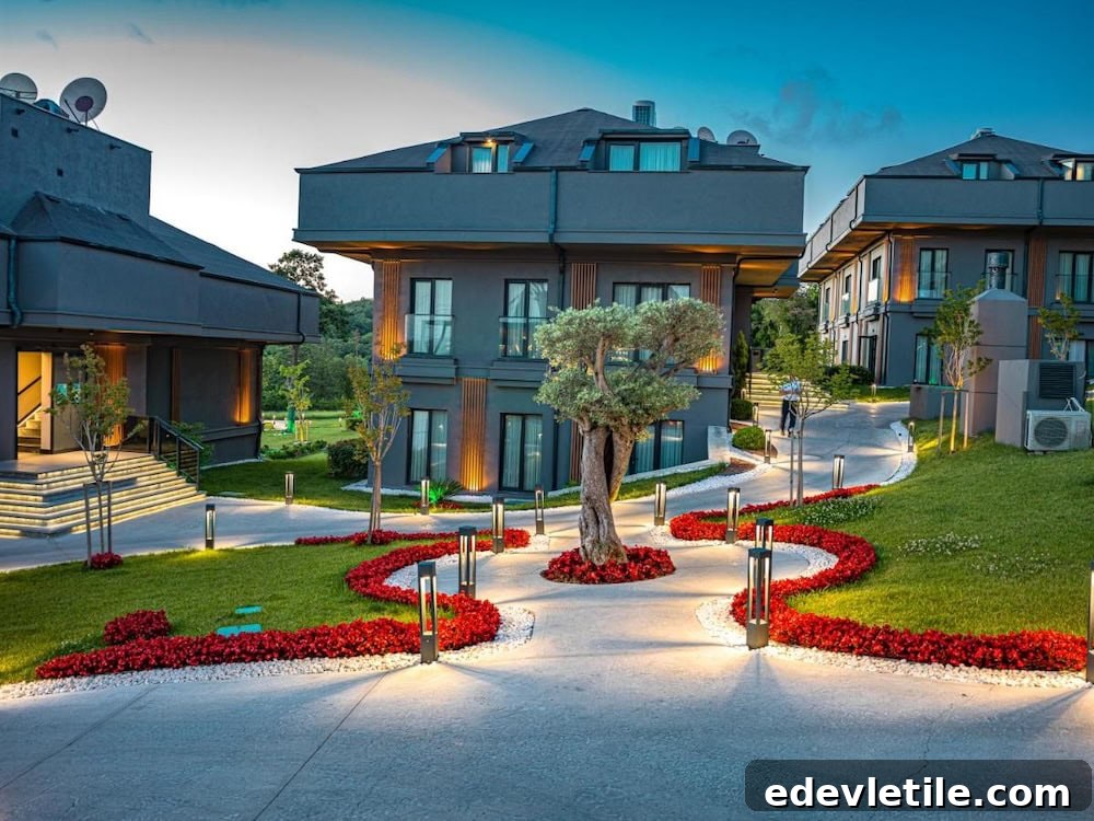 Modern, upscale building of Menalo Airport Hotel with manicured gardens, curved walkways, and dramatic evening lighting.