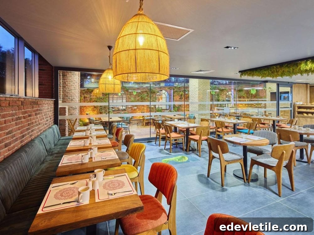 Bright and welcoming hotel restaurant with modern wooden tables, colorful chairs, and woven pendant lights.