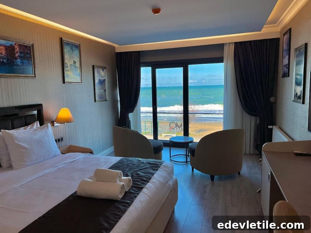 Hotel room with sea view near Istanbul Airport, featuring a double bed, seating area, and balcony overlooking the beach.