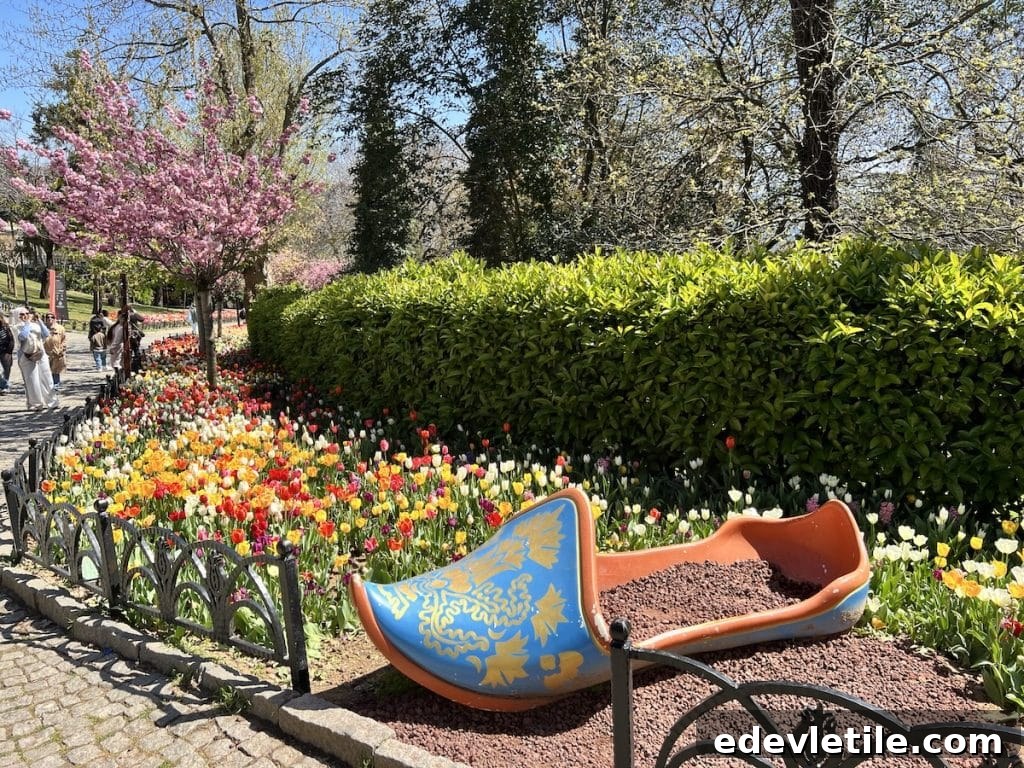 A giant ceramic tulip shoe sculpture in Emirgan Park displayed beside a walkway lined with multi-colored tulips and flowering trees.