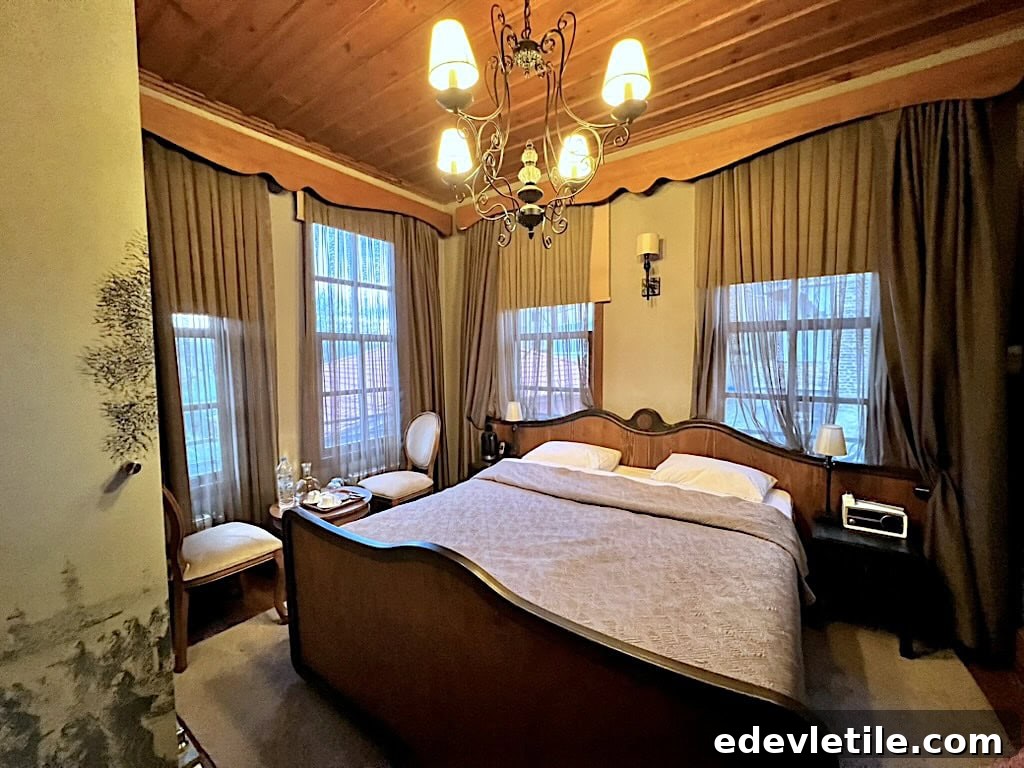 Warm, inviting hotel room called Kaf Konak with wooden ceilings, antique-style furniture, and soft natural light filtering through the curtains.