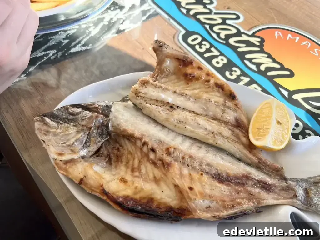 Freshly grilled fish served whole with a lemon wedge on a white plate at a local seafood restaurant in Amasra.