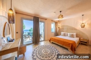 Airy hotel room with ocean views, featuring a king-sized bed with orange accents, rattan light fixtures, and a private balcony overlooking the sea.
