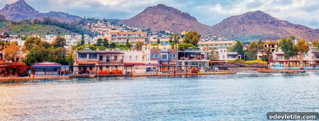 Colorful seaside buildings lining the calm bay of Akyarlar, backed by rugged hills, reflecting a peaceful, family-friendly coastal village atmosphere.