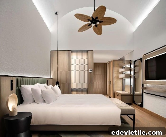 Contemporary hotel room in Akyarlar featuring minimalist wooden design, vaulted ceiling, neutral tones, and a unique petal-shaped ceiling fan.
