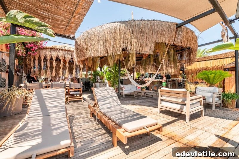 Stylish wooden deck at a hotel in Bodrum with thatched-roof cabanas, hammocks, tropical plants, and padded loungers creating a relaxed, beachy vibe.