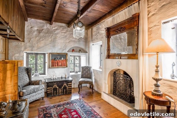 Cozy hotel room in Bodrum with traditional Turkish design, including a carved fireplace, antique furnishings, wooden ceiling, and patterned rugs.
