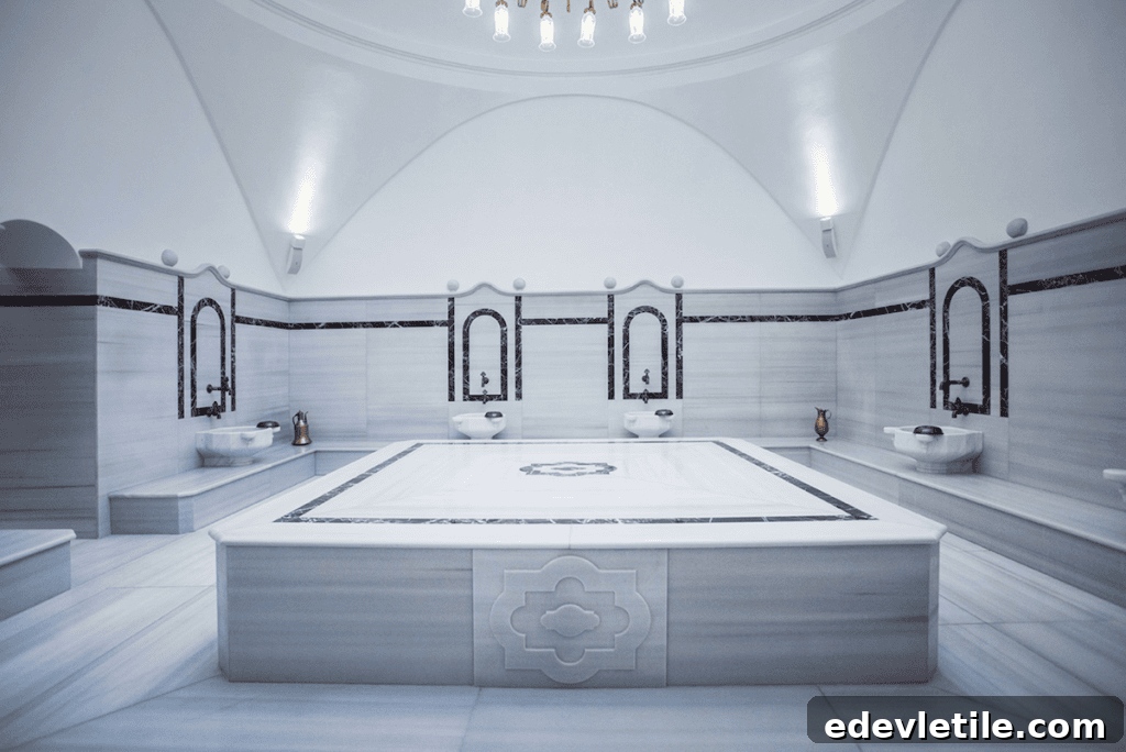 Modern and minimalist marble bath room at Cukurcuma Hamam with black tile accents and symmetrical fountains around a central heated slab.
