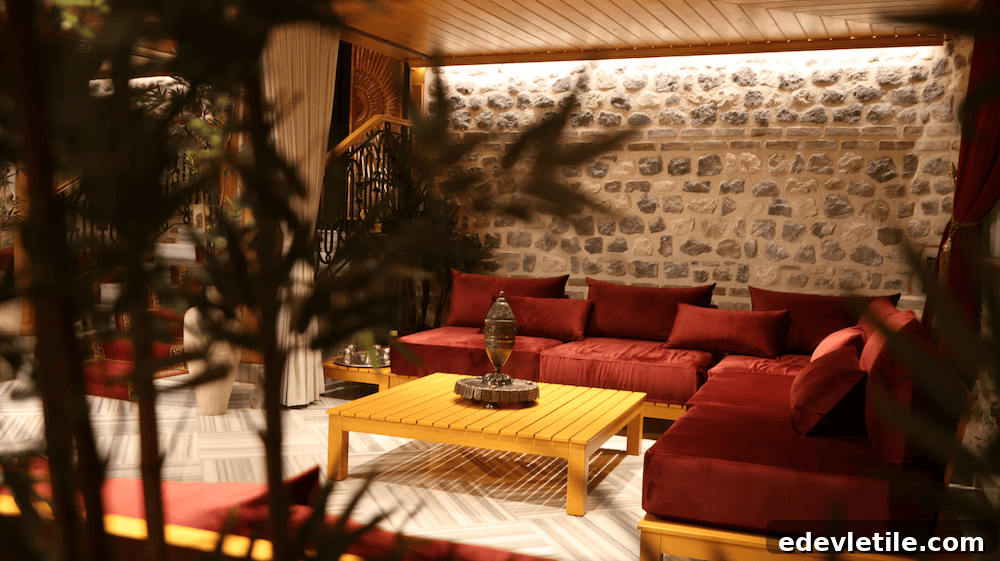 Cozy and dimly lit lounge at Çatma Mescit Hamam featuring plush red seating, a yellow wooden table, and a stone accent wall.