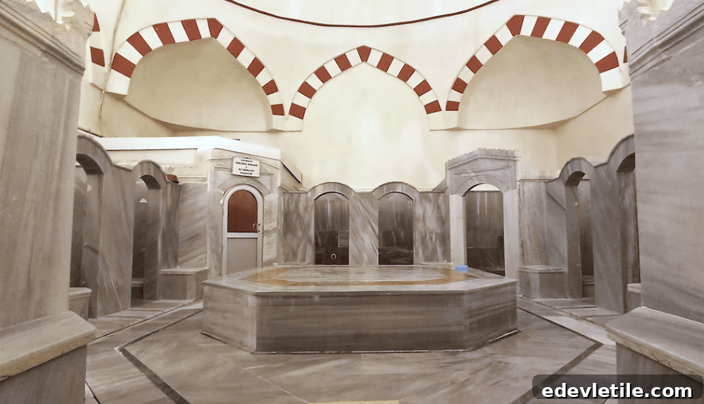 Historic stone interior of Çinili Hamamı with red-and-white striped arches, private alcoves, and a central heated marble slab.
