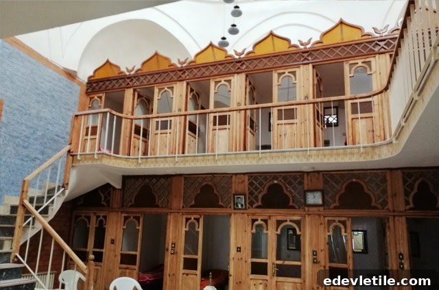 Traditional wooden changing cabins with pointed arch designs arranged across two levels at Çinili Hamamı, beneath a vaulted white ceiling.