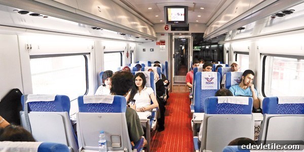 Interior of a high-speed train in Turkey, with passengers seated in blue chairs, some working or chatting, others relaxing.