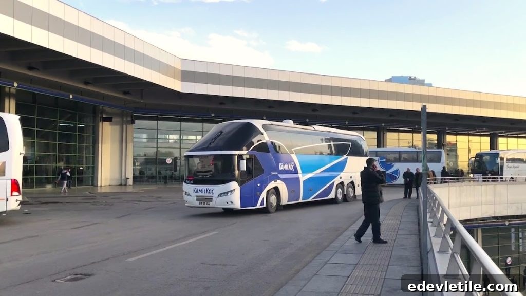 A Kamil Koç intercity bus parked at a modern Turkish bus terminal, with a few travelers walking nearby.