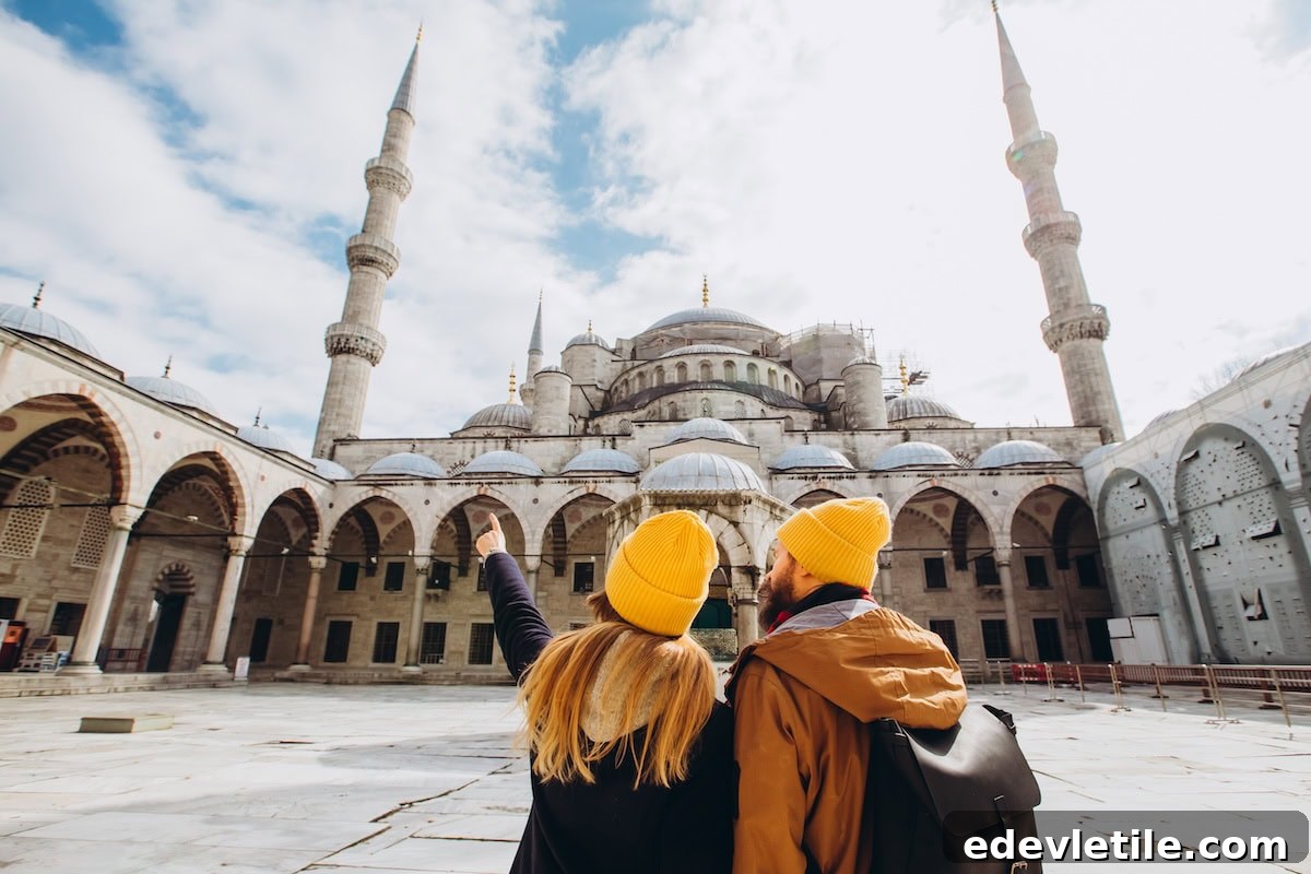 Couple wearing matching yellow beanies admiring the iconic Blue Mosque in Istanbul from its grand courtyard.