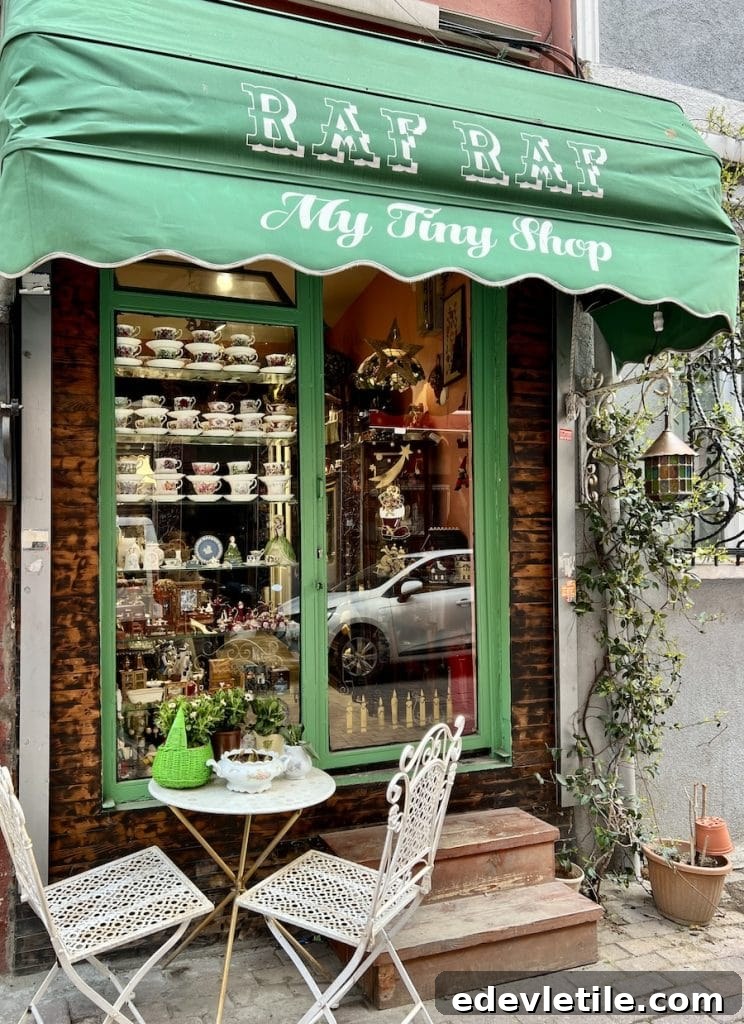 Quaint antique shop “Raf Raf My Tiny Shop” in Balat with a green awning, tea cups in the window, and a small white patio table set outside.