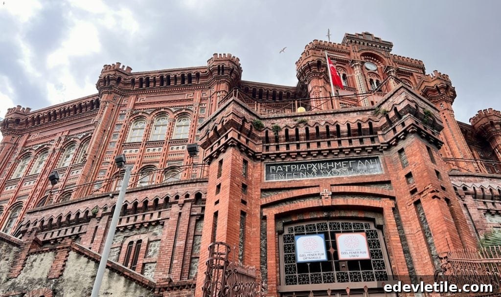 Dramatic view of the red brick Fener Greek Orthodox College in Istanbul, with intricate Neo-Gothic architecture and tall towers under a cloudy sky.