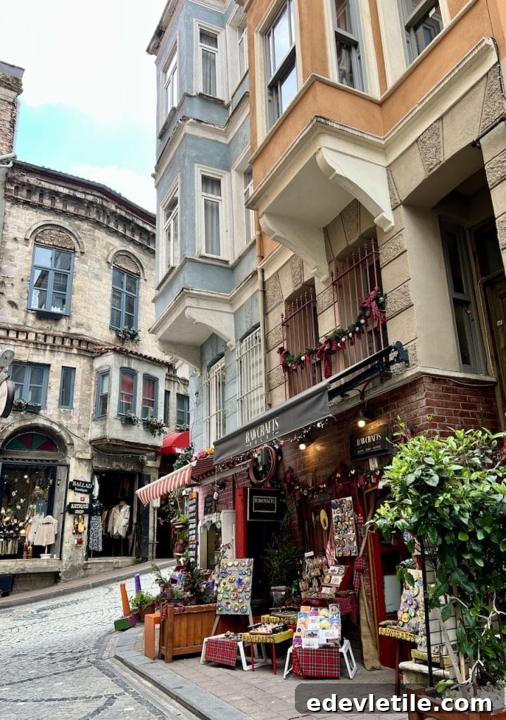 Street corner in Balat with the RAWCRAFTS gift shop surrounded by pastel-colored buildings, cobbled pavement, and handcrafted souvenirs on display.