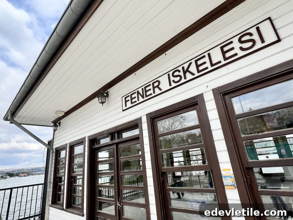 Sign reading “Fener İskelesi” (Fener Pier in Istanbul) above a wooden ferry dock building on the Bosphorus, with water and city skyline glimpsed through windows.