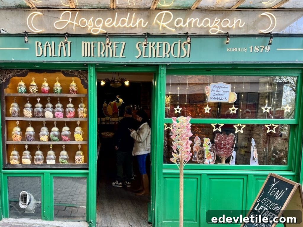 Bright green storefront of an old Balat sweet shop with glass jars of candies displayed in the window and Ramadan decorations above.