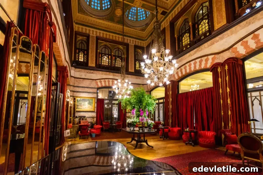 Luxurious interior of the historic Pera Palace Hotel in Istanbul, featuring chandeliers, red velvet furniture, tall ceilings, and elegant Ottoman-inspired design.