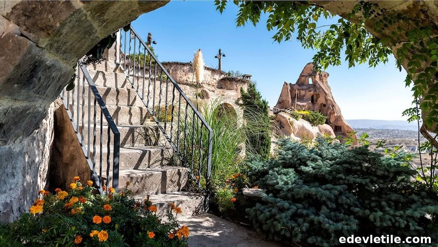 Charming garden terrace with stone steps, colorful flowers, and a scenic view of cave dwellings nestled in Cappadocia’s rocky terrain.