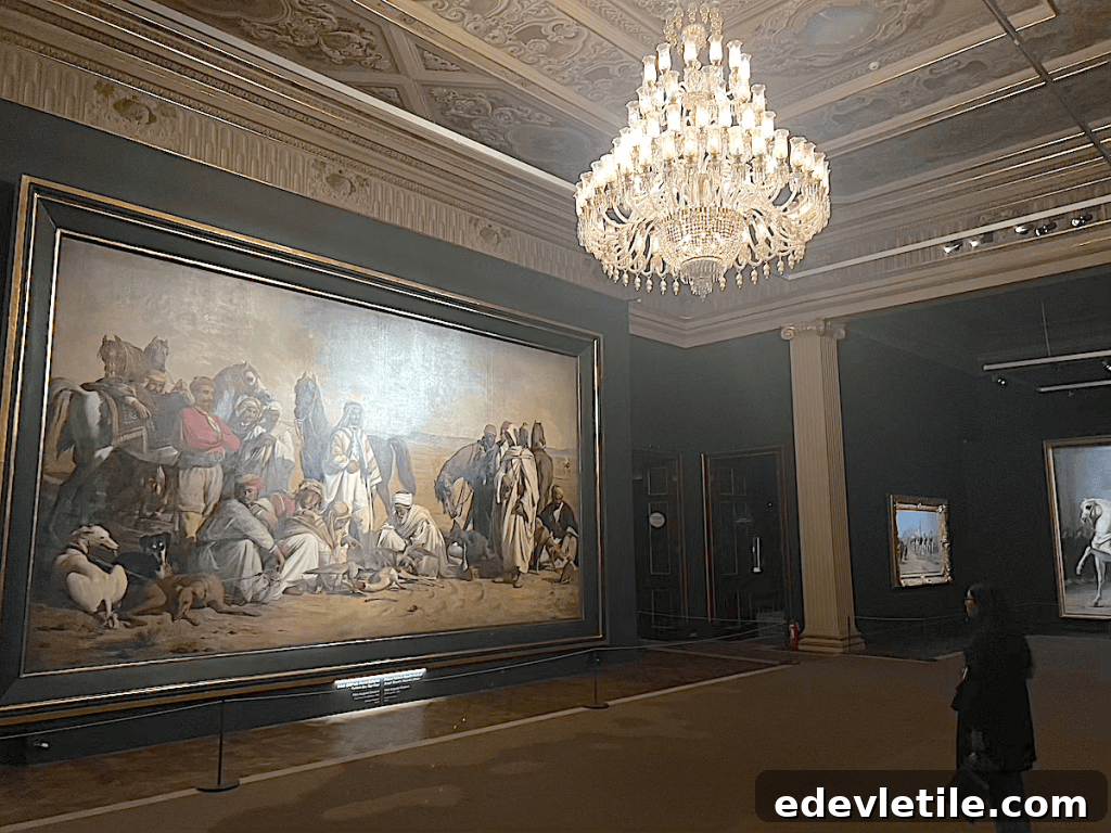 Dimly lit gallery with a large 19th-century Orientalist painting, crystal chandelier overhead, and a woman viewing the art inside the National Palace Painting Museum.