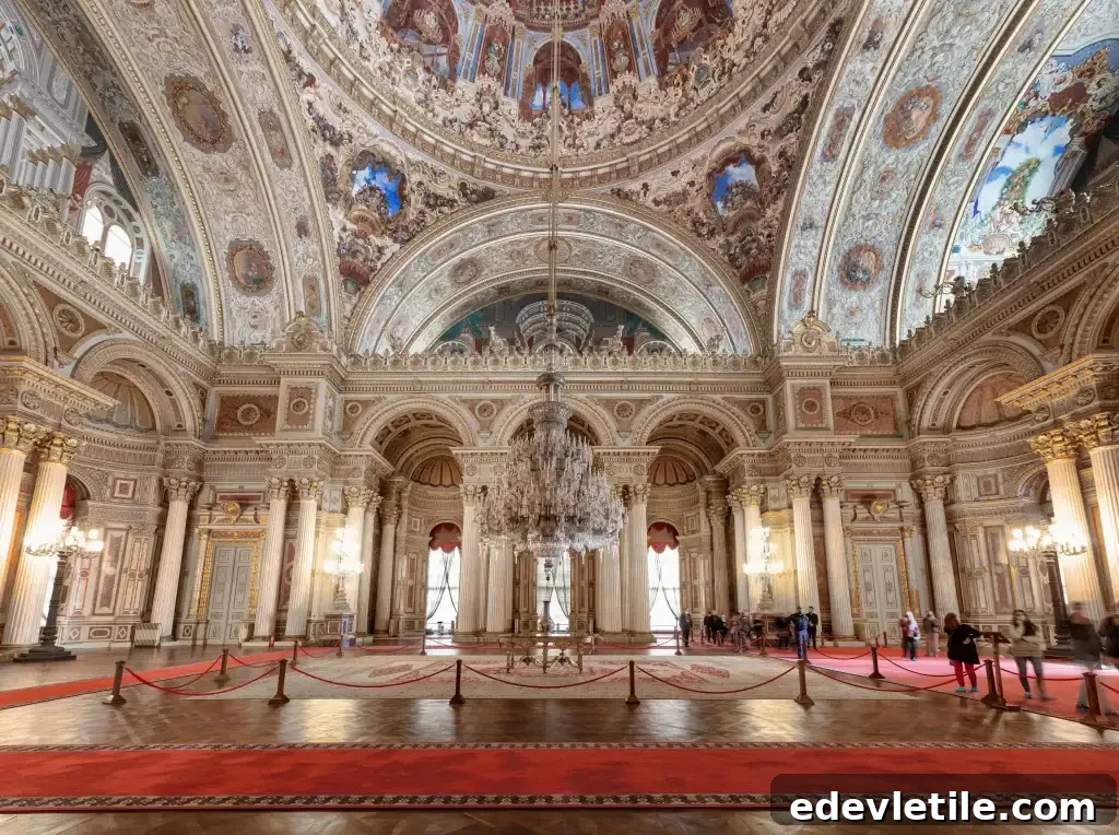 Lavish grand hall inside Dolmabahçe Palace featuring a massive crystal chandelier, arched ceilings, and red carpeted floors.