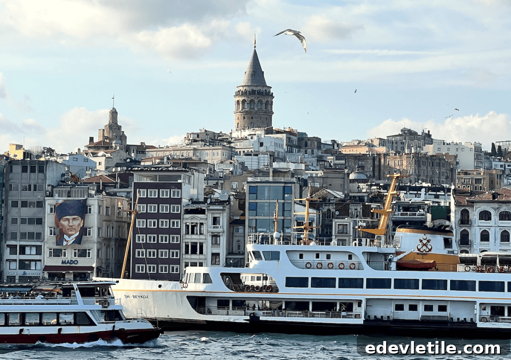 View of Istanbul’s Galata Tower rising above a dense cluster of buildings, with ferries docked along the Bosphorus and a large mural of Atatürk on one of the facades.
