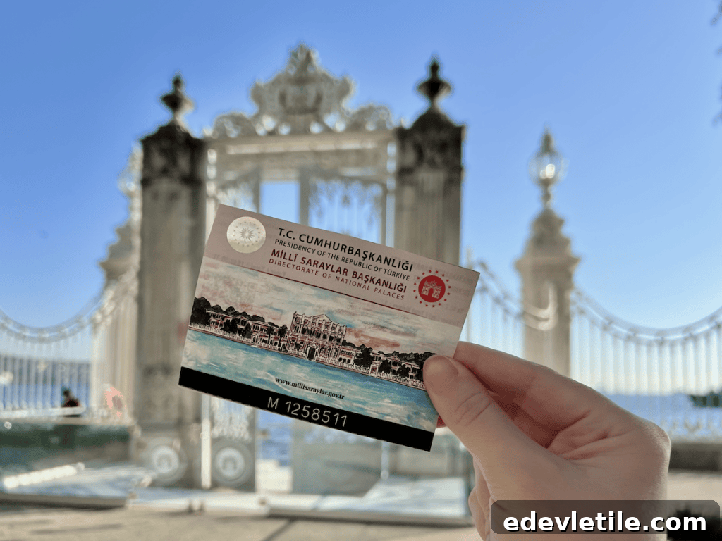 Close-up of the author holding a Dolmabahçe Palace ticket with the palace’s seaside gate blurred in the background.