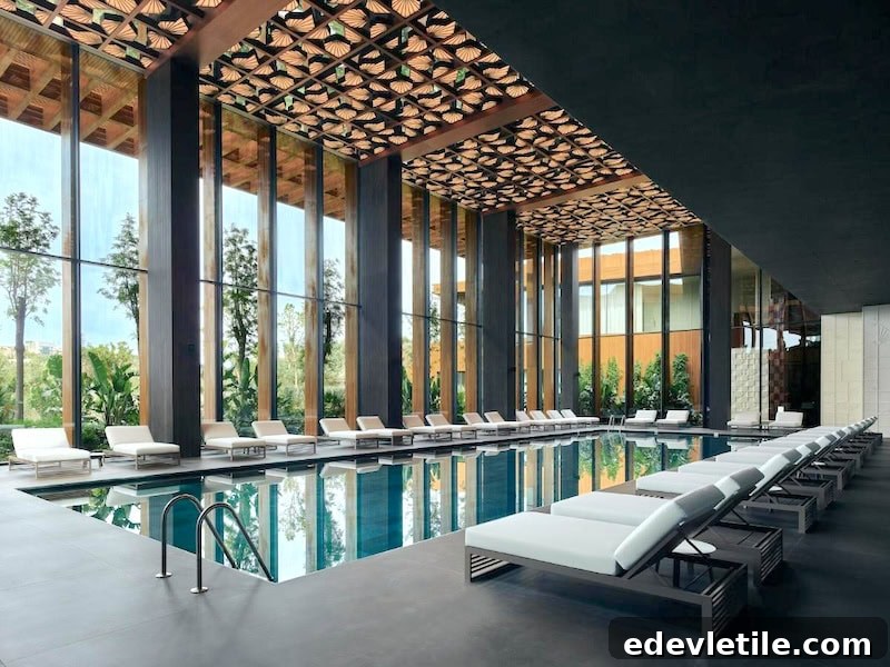 Luxury indoor swimming pool at a modern Turkish hotel, with floor-to-ceiling windows, lounge chairs, and intricate ceiling design.