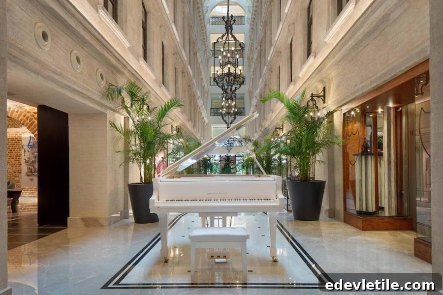 Grand central atrium of JW Marriott Istanbul Bosphorus featuring a white piano, marble floors, tall palms, and hanging chandeliers.