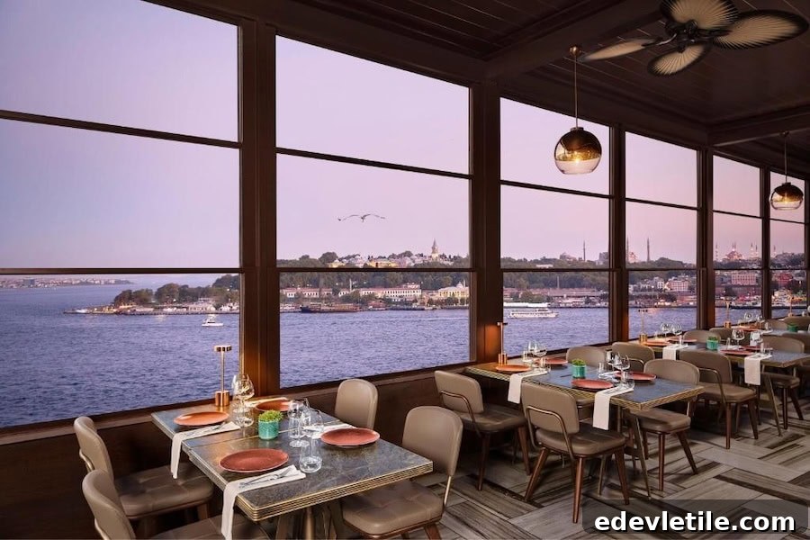 Elegant indoor dining area at JW Marriott Istanbul Bosphorus with panoramic windows overlooking the Bosphorus at sunset.