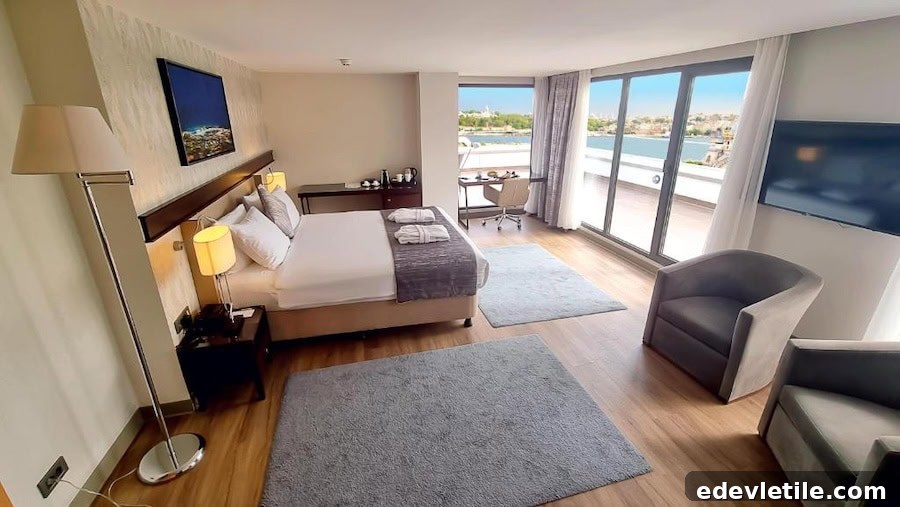 Cozy, modern guest room at Port Bosphorus Hotel with balcony doors opening to a bright sea view and stylish neutral decor.