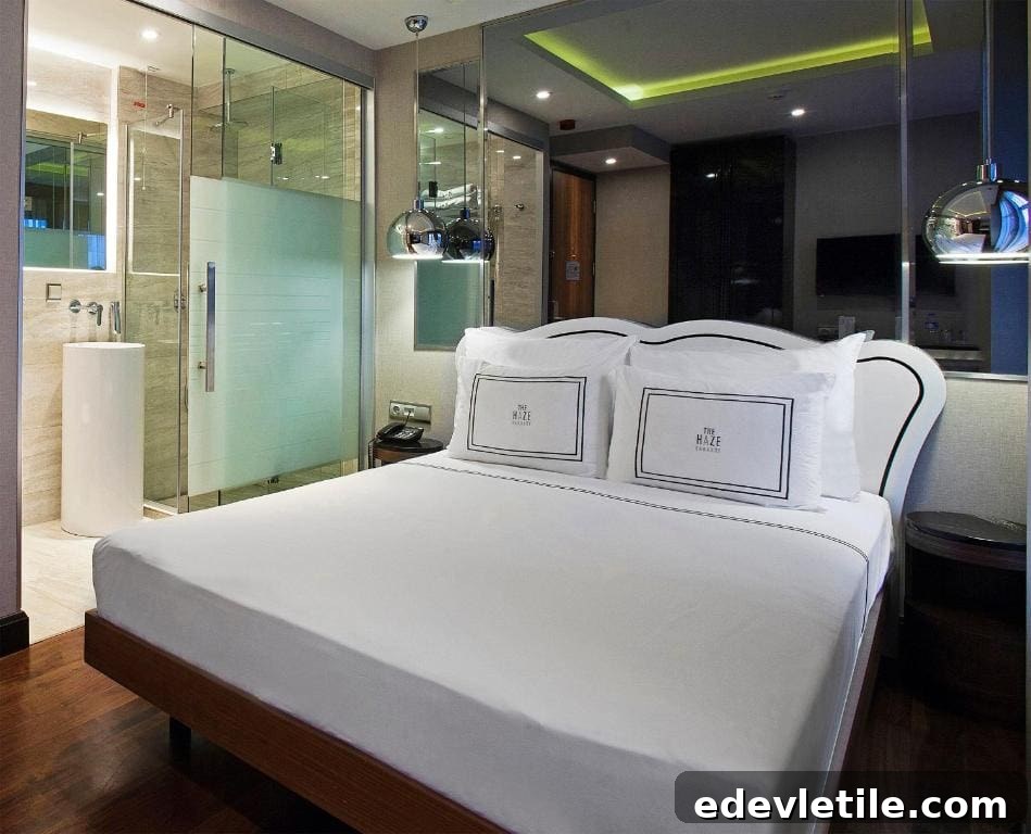 Compact yet luxurious room at The Haze Karaköy featuring a plush bed and modern bathroom with glass partition and ambient lighting.