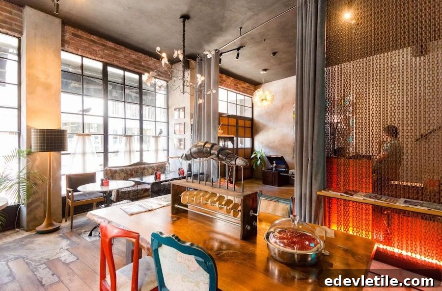 Eclectic lobby at SuB Karaköy Hotel with mismatched chairs, warm lighting, vintage decor, and large factory-style windows.