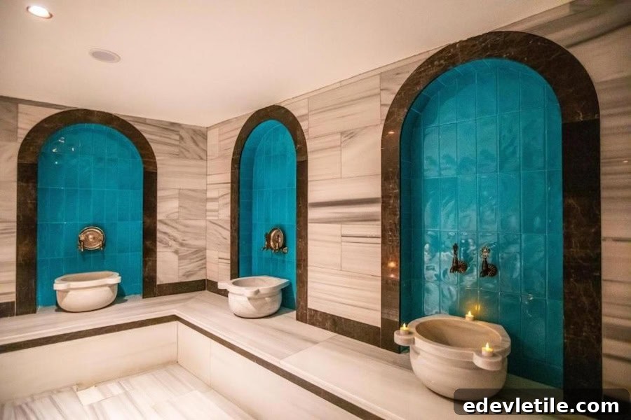 Turkish bath at SuB Karaköy Hotel with three marble basins set in vivid blue-tiled arches, framed by classic white marble walls.