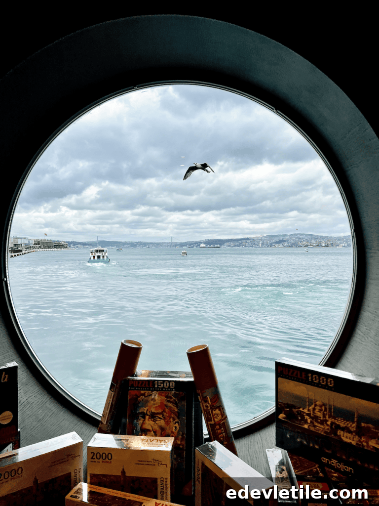 Circular window view from Galataport overlooking the Bosphorus, with boats in the water and Istanbul’s hills in the distance.