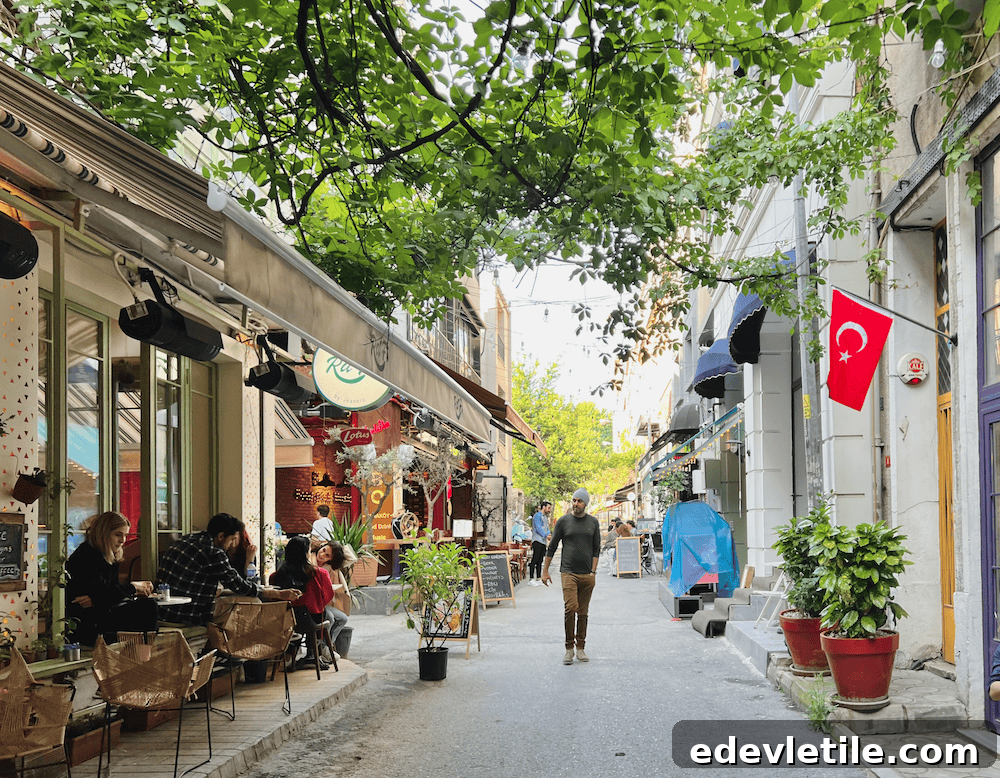 Cozy, cafe-lined pedestrian street in Karaköy with hanging lights and leafy trees.