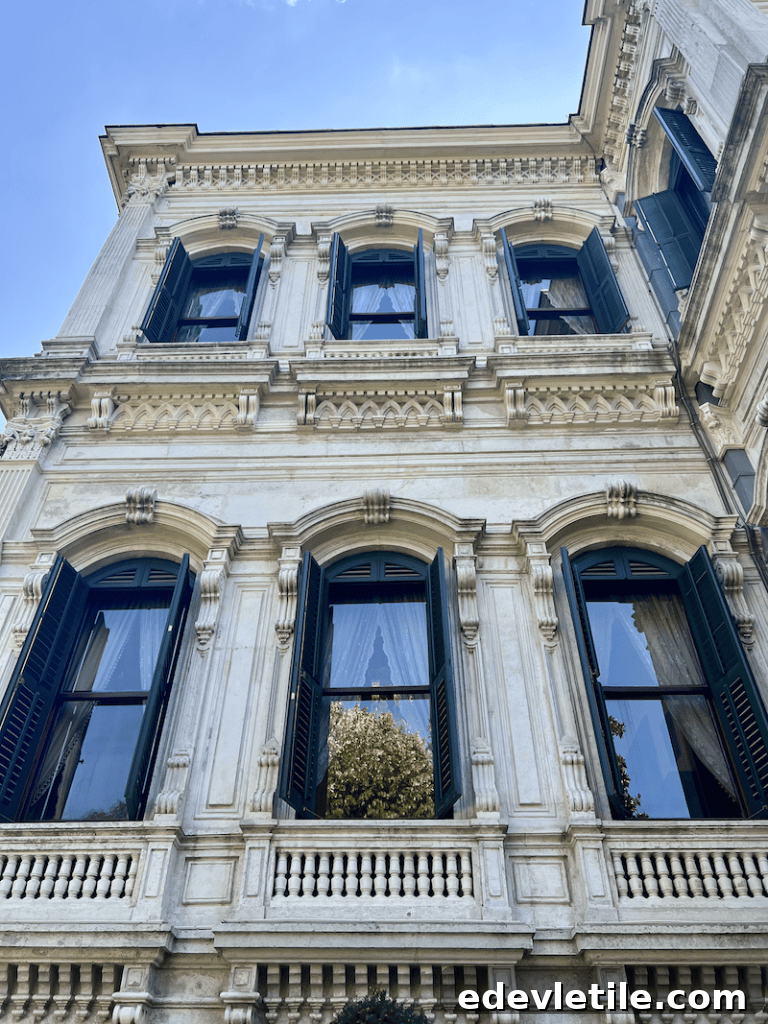 Upward view of Yıldız Palace’s intricately framed windows with black shutters and delicate lace curtains, highlighting Ottoman-European architectural fusion.