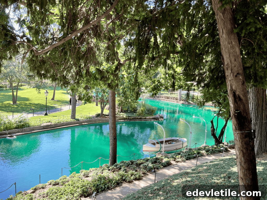 Tranquil pond with turquoise water and a small Ottoman-style wooden boat, surrounded by trees and greenery in the palace gardens.