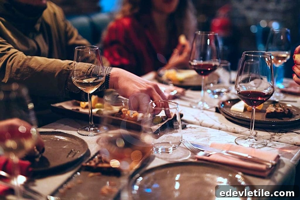 A close-up of a stylish dinner table set with wine glasses, cheese, and gourmet small plates, as people reach in to share food during a high-end tasting experience in Istanbul.
